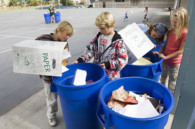 Three children recycling at their school.