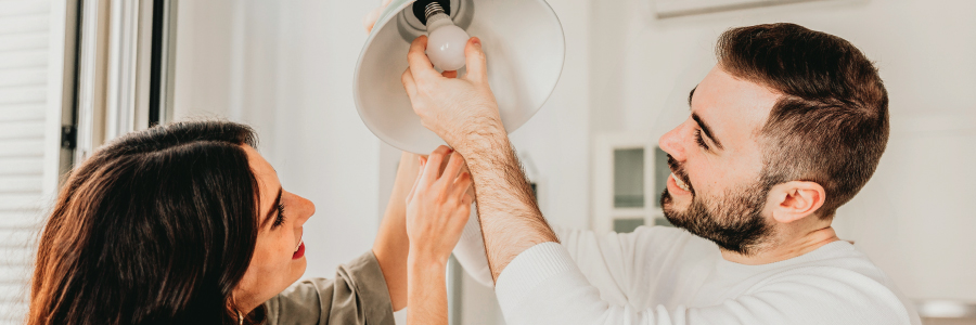 A young couple changing a light bulb together.