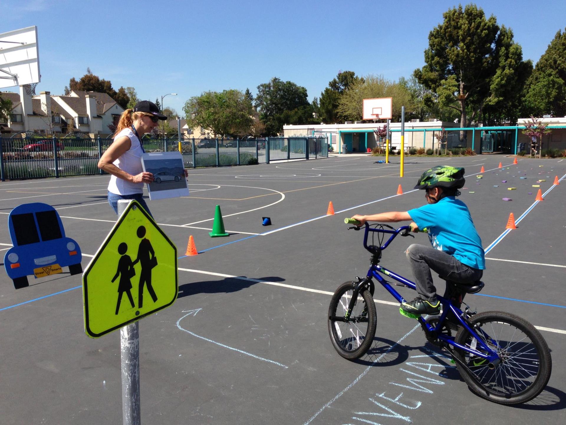 An instructor teaching a student on a bicycle about bicycle safety