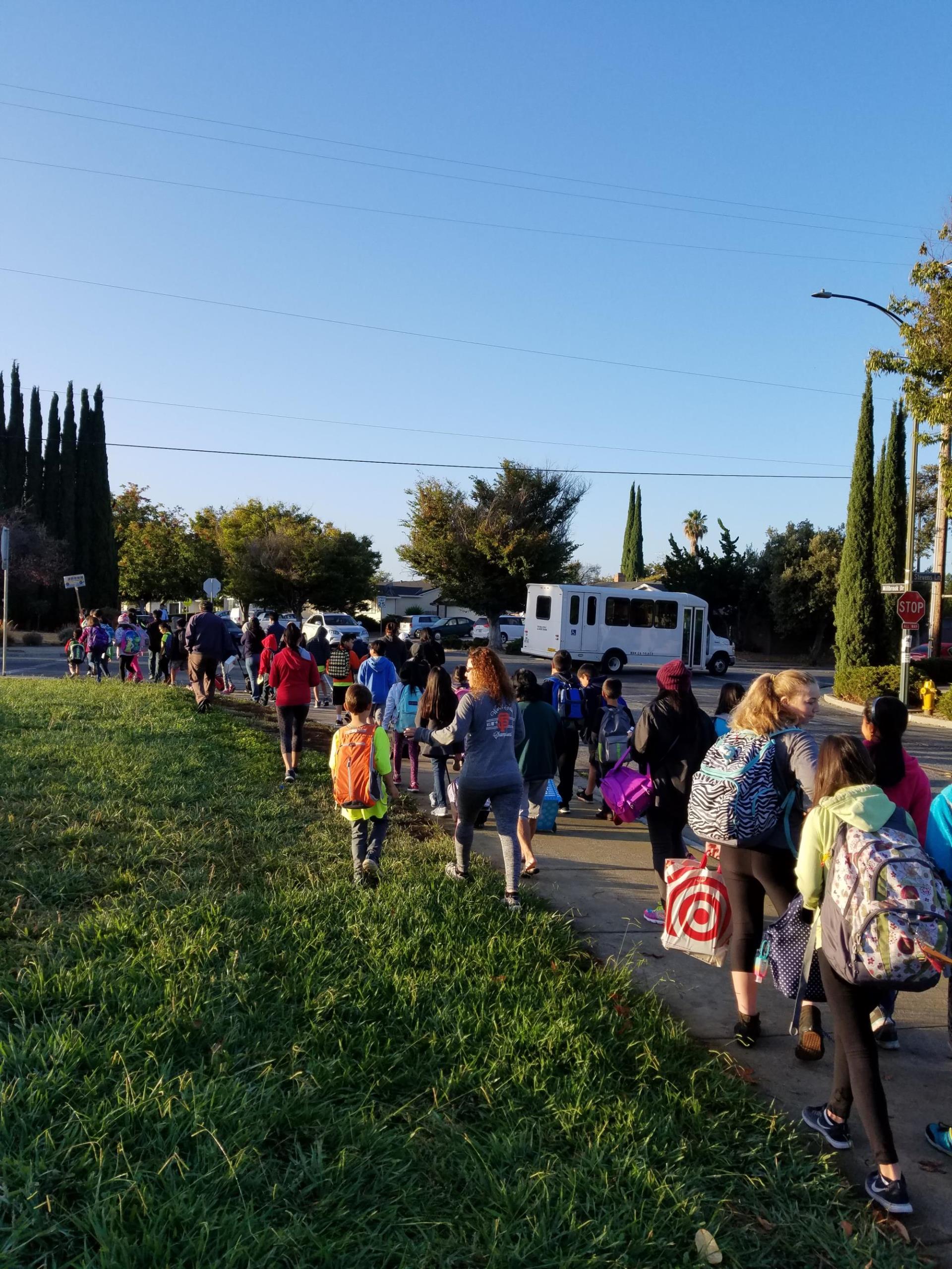 A large group of children, families, and teachers walking