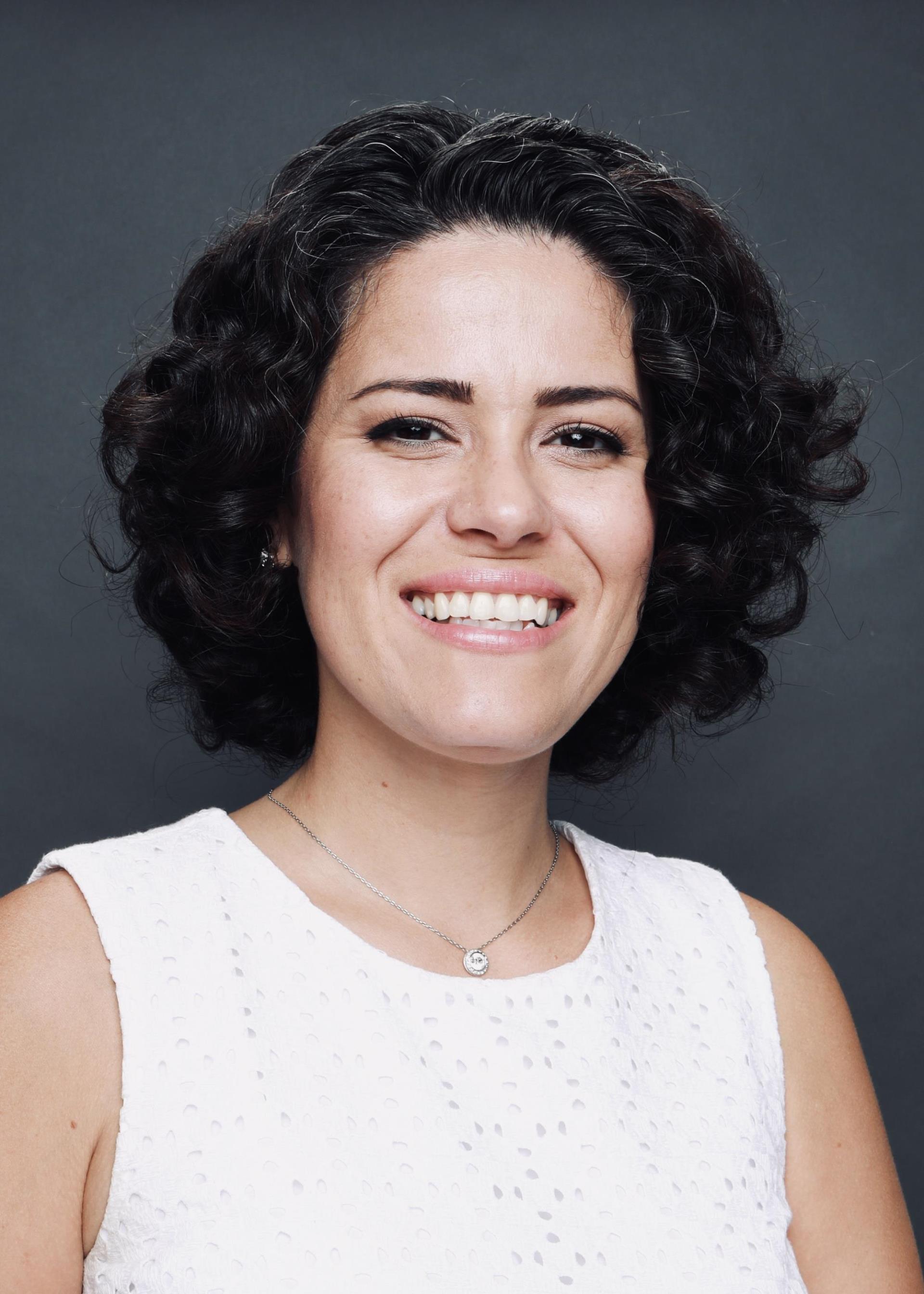 Headshot Image of Sarah Zarate wearing a white shirt with a dark grey background