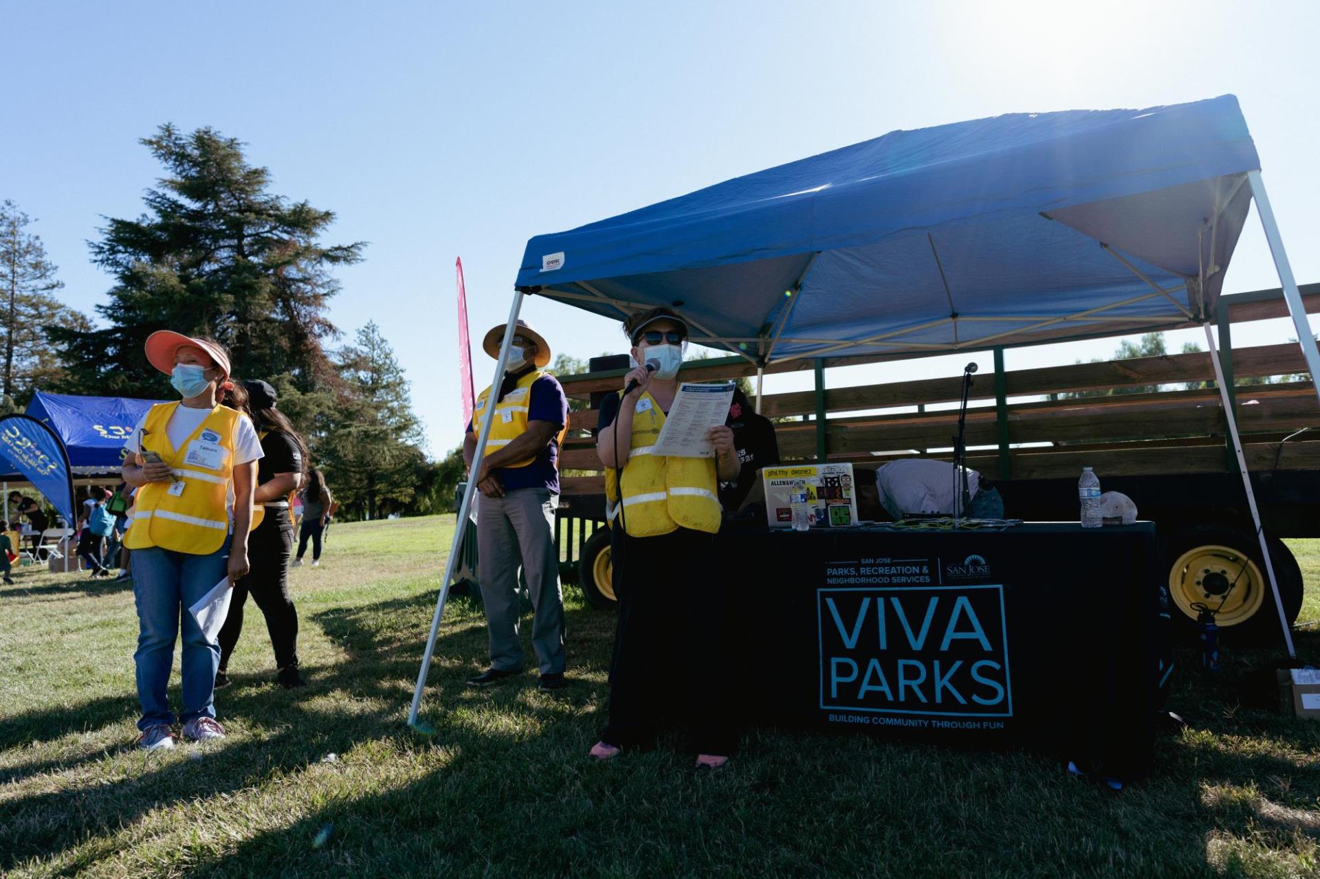 People in yellow vests by the Viva Parks table and tent making announcements.