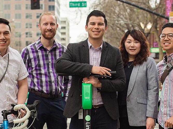 Five Department of Transportation staffers standing with a scooter and a bicycle