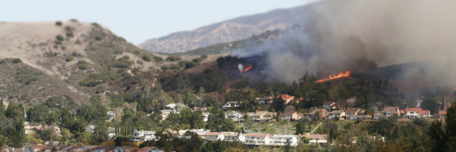 A wildfire in a suburban area near a hillside.