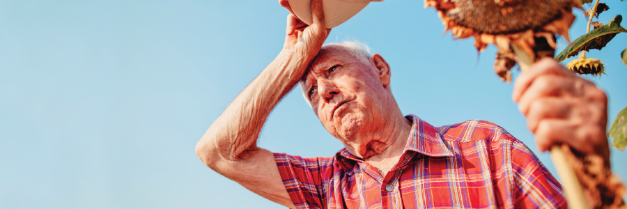 An older adult wiping his head from the hot weather.