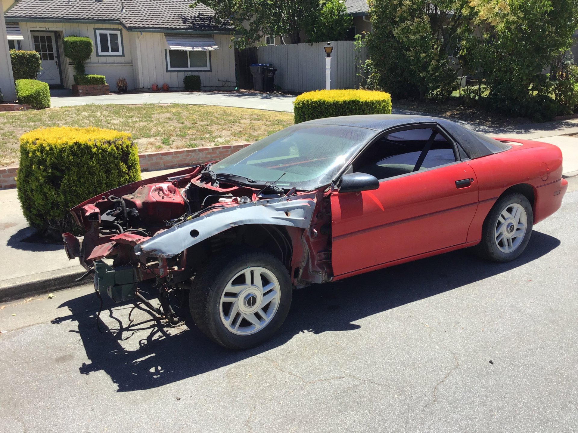 A red car missing an engine and bumper.