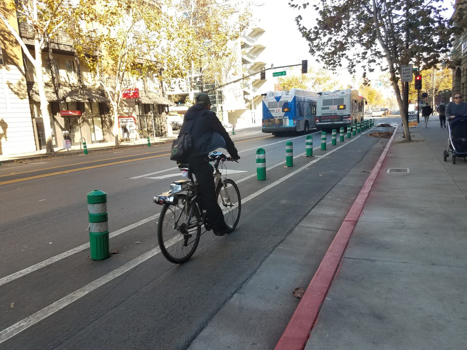 A protected bike lane, surrounded by green plastic bollards, on San Fernando Street