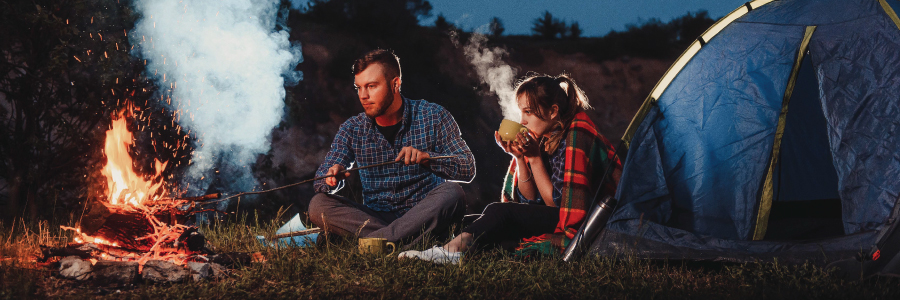 A young couple enjoying a campfire.