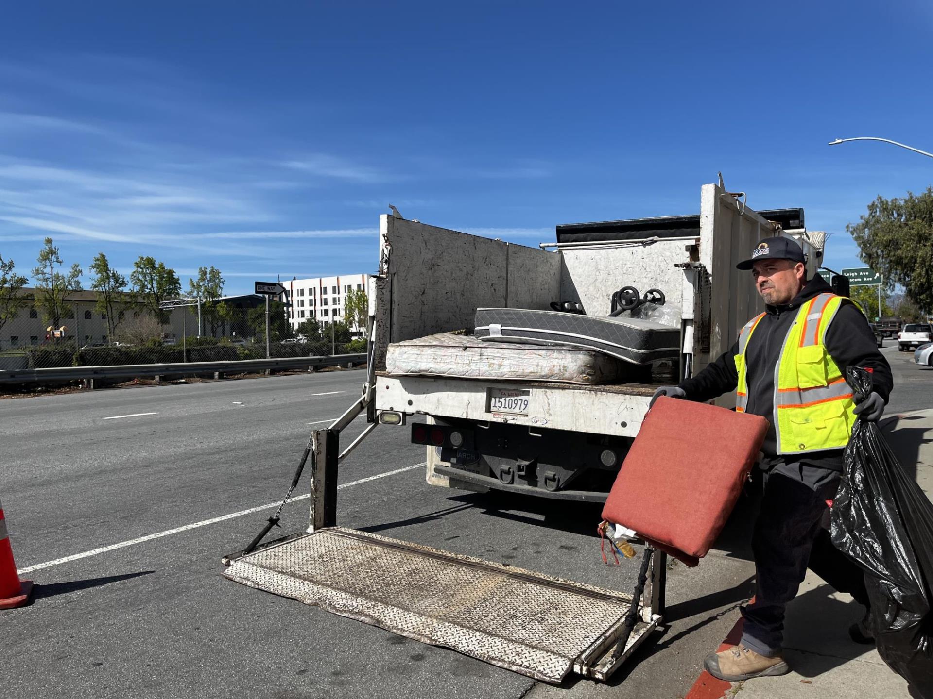 BeautifySJ staff in a green vest loading the truck with illegal dumping