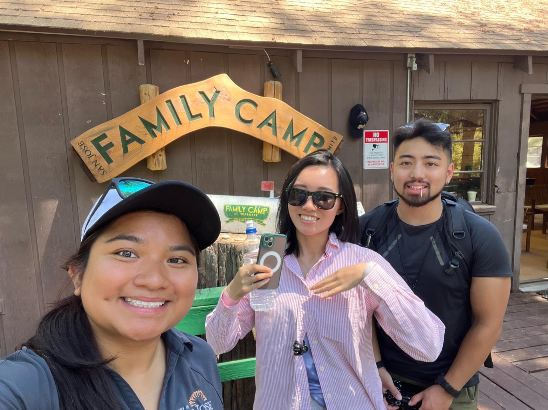 Three PRNS employees pose in front of Family Camp sign