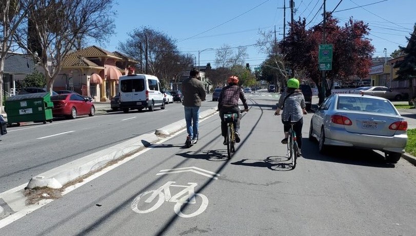 Three people riding bikes in a frontage lane