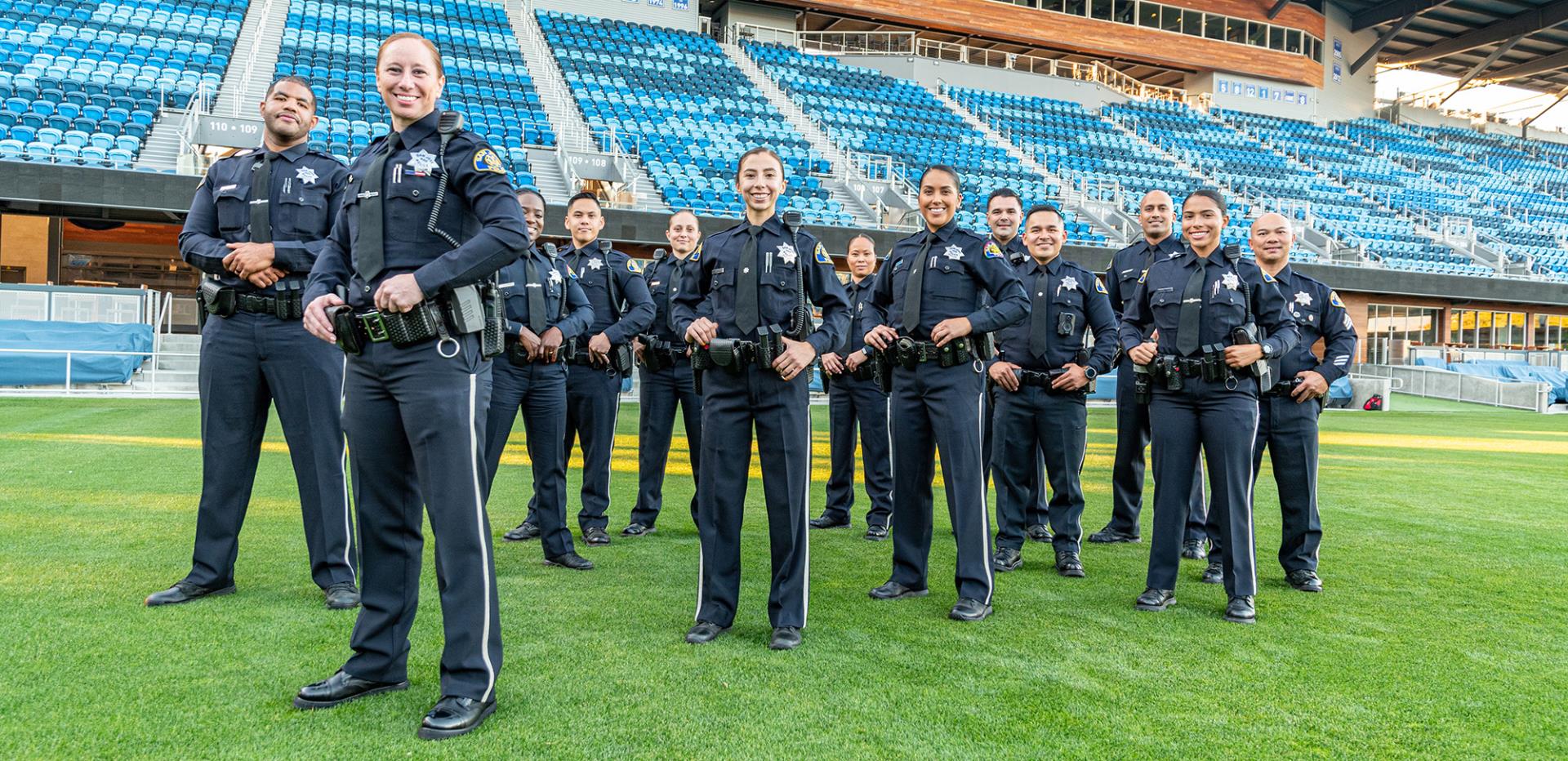 A group of San Jose police officers stand on the field at PayPal Park on a sunny day