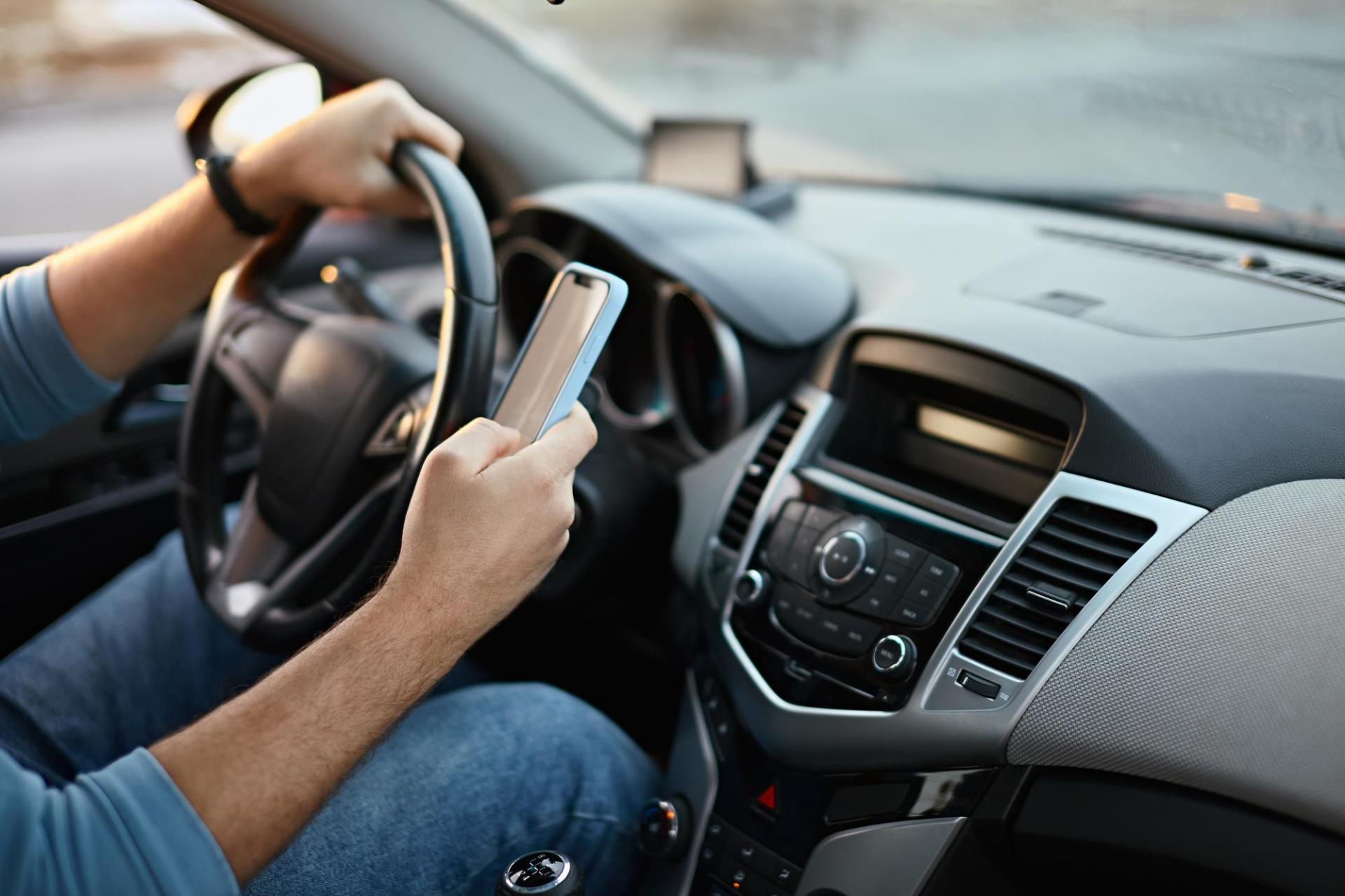 A person looking at their smartphone while driving