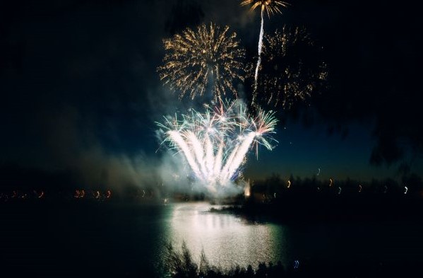 Fireworks illuminate the night sky at Almaden Lake Park. Residents sitting by the lake watch the fireworks shimmer in shades of red, blue, bright white, and gold.