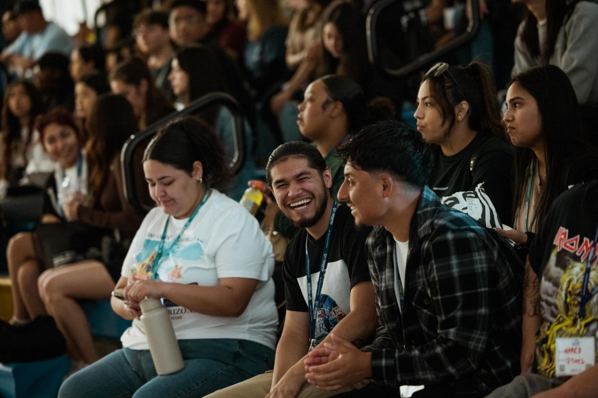 Recreation leaders are seated on bleachers. In the front, two recreation leaders are turned towards each other and laughing