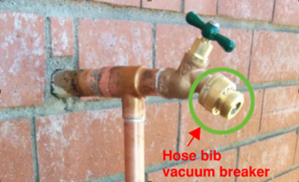 Faucet coming out of a brick wall with the hose bib vacuum breaker circled in green with an arrow pointing at it