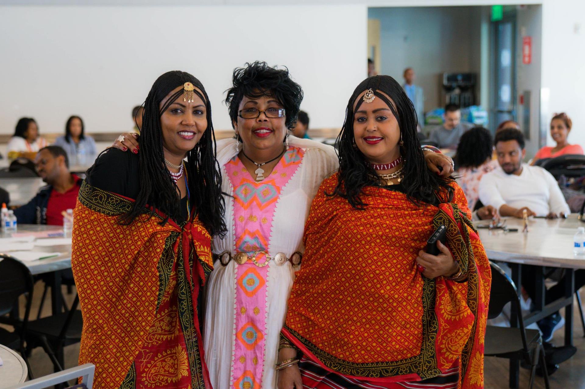 Three women standing facing toward the camera smiling.