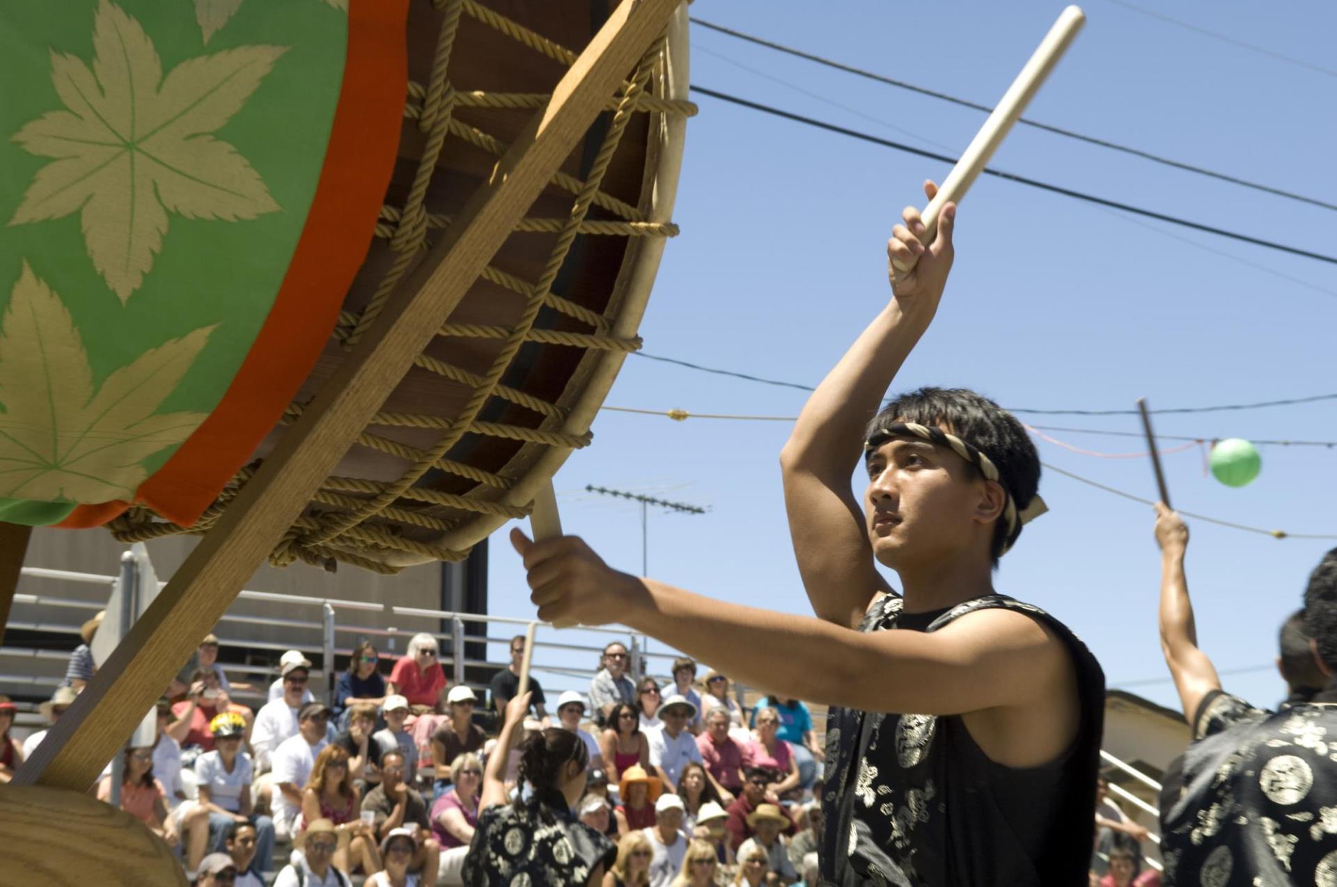 A man standing and holding a drumstick, looking towards a large drum.