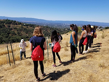 Volunteers standing on a brown hill being trained to help