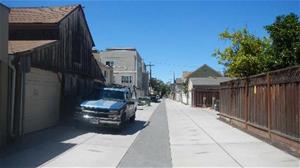 A narrow alleyway recently paved with permeable pavers running along in the middle of alley