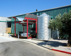 A tall and big rain barrel, placed next to a public art structure 