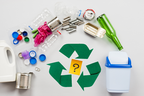 A green recycling symbol with a question mark in middle, surrounded by items to dispose, going into a recycling bin